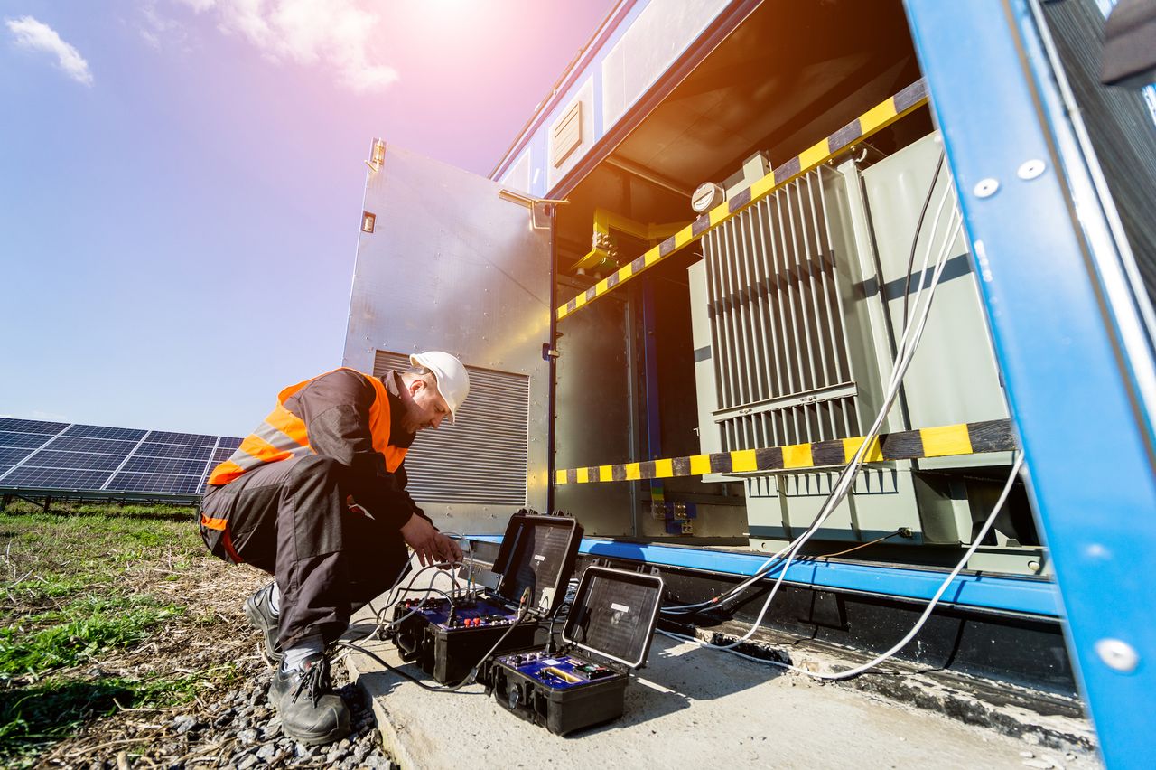 Techniker bei der Kontrolle der elektrischen Komponenten einer PV-Freiflächenanlage